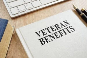 Veteran Aid and Attendance Benefit book and laptop on table